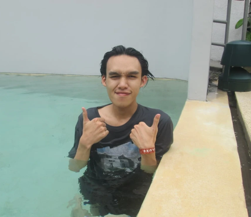 Dimas giving a thumbs up near a swimming pool.